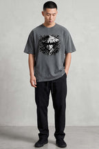 Man wearing a gray t-shirt with a graphic design on a plain background
